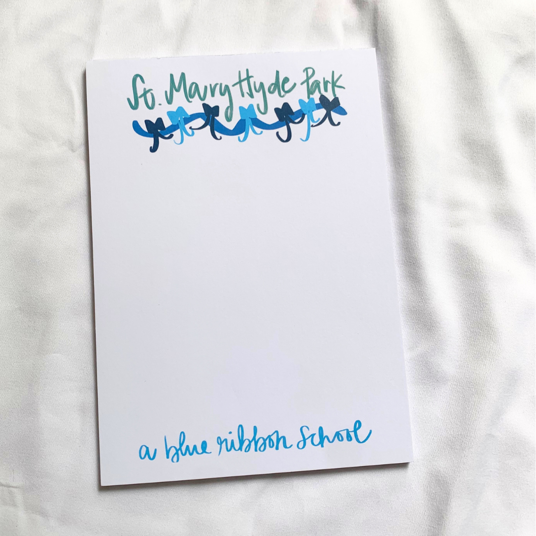 Notepad with 'St. Mary Hyde Park' and 'a blue ribbon school' text, indicating it is associated with a Blue Ribbon award. Text is handwritten in green and blue. Blue bow design is under the top text.