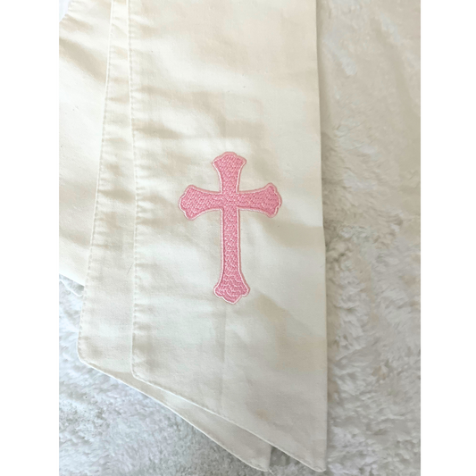 A white wreath sash with a pink embroidered cross on one side to hang on your wreath. 