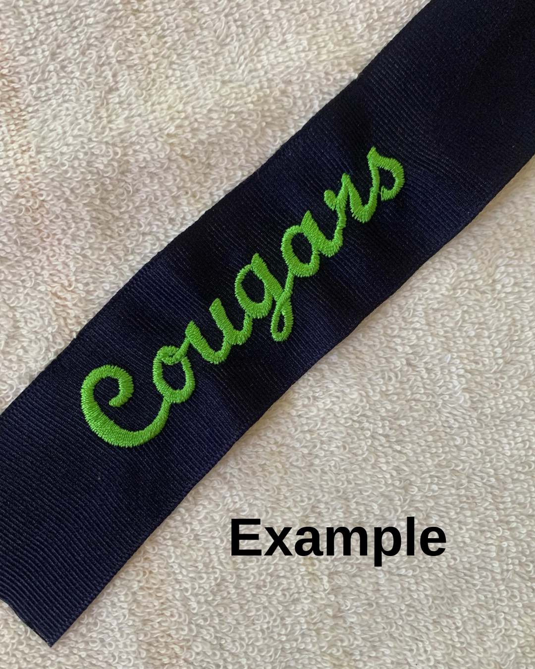 Navy blue hair ribbon with green 'Cougars' embroidered in script font. 